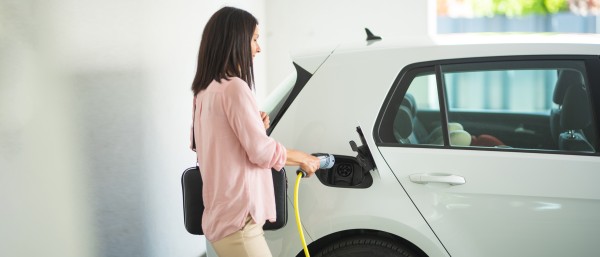 Woman plug in a charging cable in an electronic car