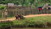 Kinder in einem laotischen Dorf spielen am Fluss.