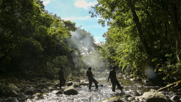 Rangers wade a river in the protected forest of the Annamite Range.