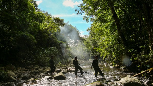 Rangers wade a river in the protected forest of the Annamite Range.