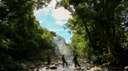 Rangers wade a river in the protected forest of the Annamite Range.