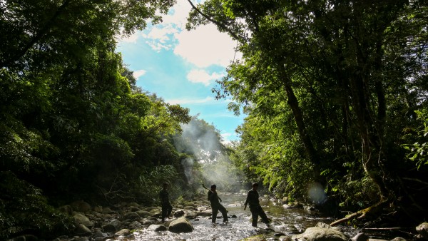 Rangers wade a river in the protected forest of the Annamite Range.