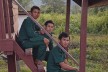 Three rangers sit on stairs in a village in Laos.