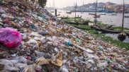 Müll und Plastikverschmutzung am Flussufer in Dhaka, Bangladesch, Flussufer und Boote im Hintergrund