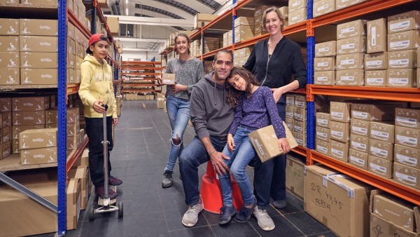 Familie Yona zwischen Regalen mit Schuhkartons