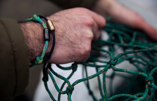 Männerhand mit Armband aus einem gebrauchtem Fischnernetz