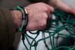 Männerhand mit Armband aus einem gebrauchtem Fischnernetz