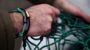 Männerhand mit Armband aus einem gebrauchtem Fischnernetz