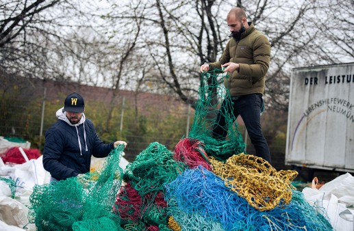 Zwei Männer stehen auf alten Fischernetzen, die gerade beim Unternehmen Bracenet ankommen