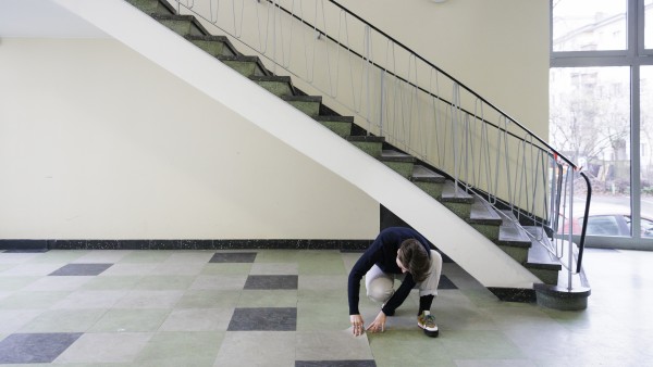 A woman checks the floor tiles at the foot of a staircase 