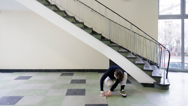 A woman checks the floor tiles at the foot of a staircase 