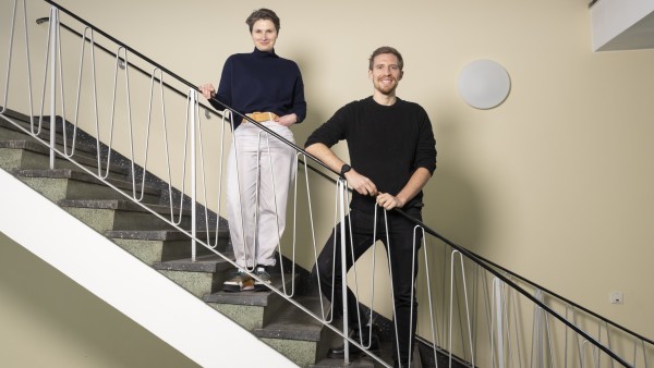 A man and a woman stand smiling at the banisters 