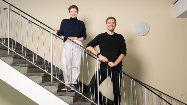 A man and a woman stand smiling at the banisters 