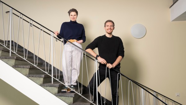 A man and a woman stand smiling at the banisters 