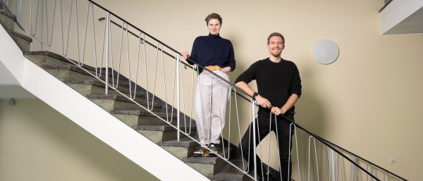 A man and a woman stand smiling at the banisters 