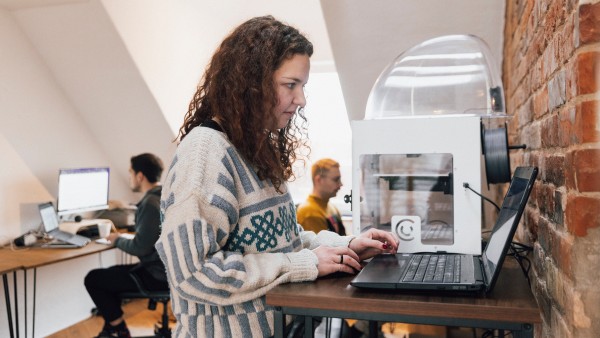 Mitarbeiterin arbeitet stehend im Gemeinschaftsbüro am Laptop