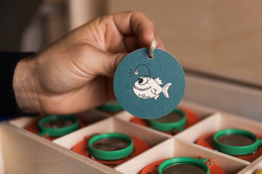 Hand holds a round pendant with a fish print