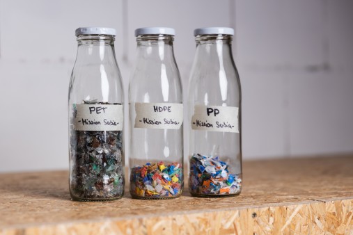 Three glass bottles filled with various small plastic parts.