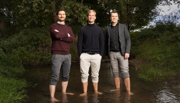 Portrait of three men, standing barefoot in a small river