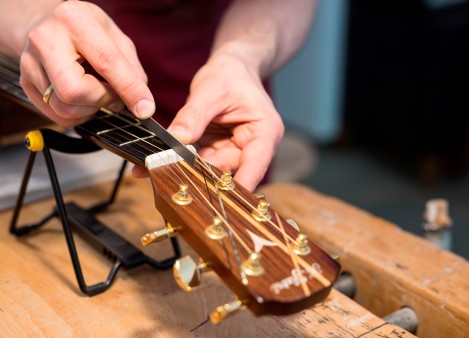 Martin Meckbach kerbt den Sattel einer Gitarre mit der Sattelfeile