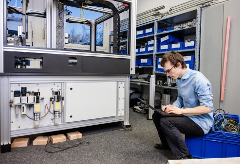 Christof Reuter, einer der vier Gründer der Kamedi GmbH in Karlsruhe mit einem Notebook an der Produktionsanlage