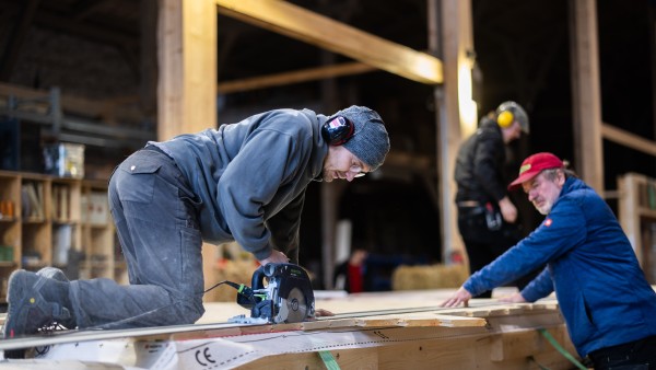 Mitarbeiter von Halm schneiden Holzrahmen zu