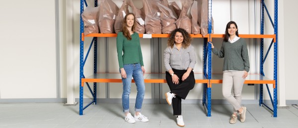 The three founders in front of a shelf