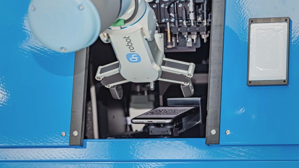 Roboterarm greift in eine Maschine in Richtung eines Smartphones