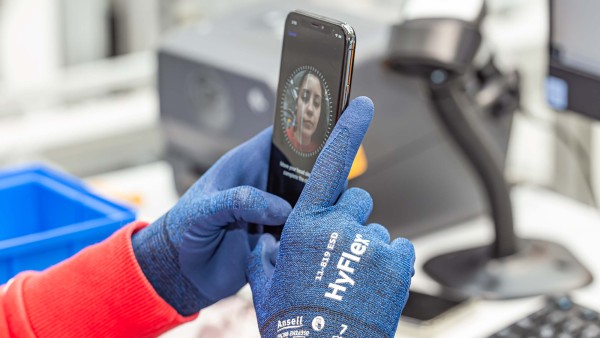 Hands hold a smartphone with a woman's face on the screen.