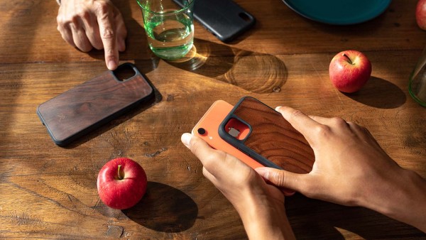 Hände nehmen Hülle von Smartphone über einem Tisch mit Äpfeln ab.