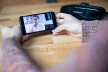 Therapy sessions take place via video call. Two hands hold a smartphone during a session.