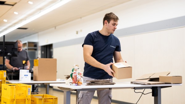 A worker packs a promotional giveaway box at a table.