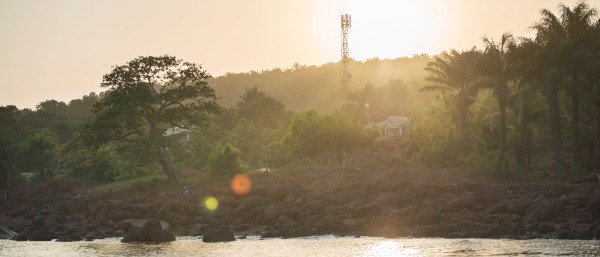 A mobile phone mast on the coast of Guinea. In the foreground is the sea.