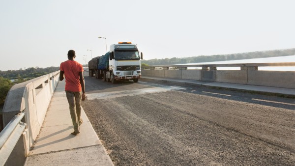 Ein Mann geht über die Brücke, ein LKW kommt ihm entgegen