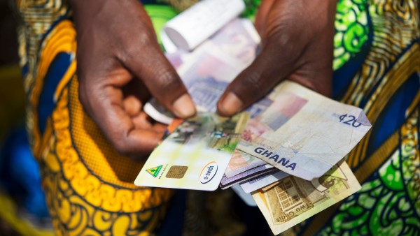 e-zwich-Karte und Banknoten in den Händen einer Frau aus Ghana