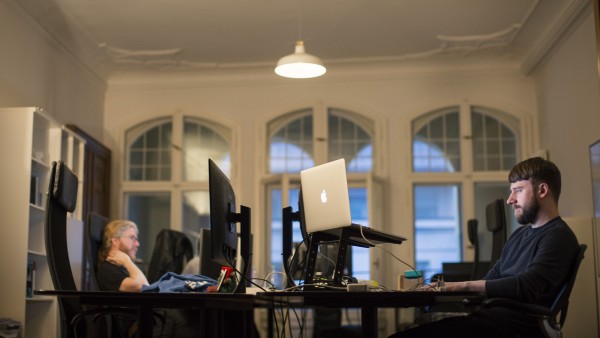 Zwei Männer sitzen sich an einem Bürotisch gegenüber und arbeiten an ihren Rechnern