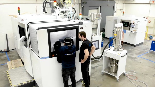 Two men standing in front of a large machine at the production site