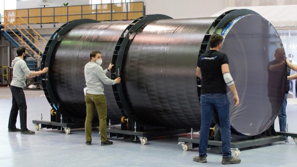 Employees handle a large round component of a rocket. 