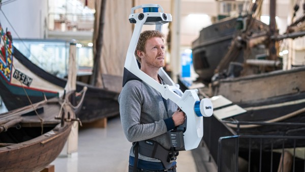 man with mobile mapping system in a warehouse with boats.