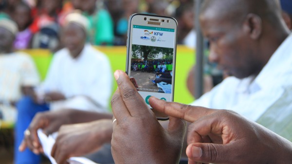 A person films people in a square with a smartphone