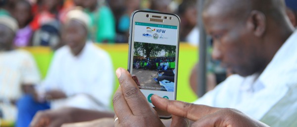 A person films people in a square with a smartphone