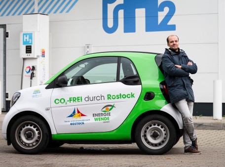 Julian Müller (betriebliches Mobilitätsmanagement) mit einem elektrisch angetriebenen Smart an einer Wasserstofftankstelle in Rostock