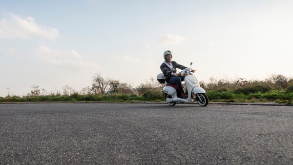 Man driving a scooter on a asphalt road