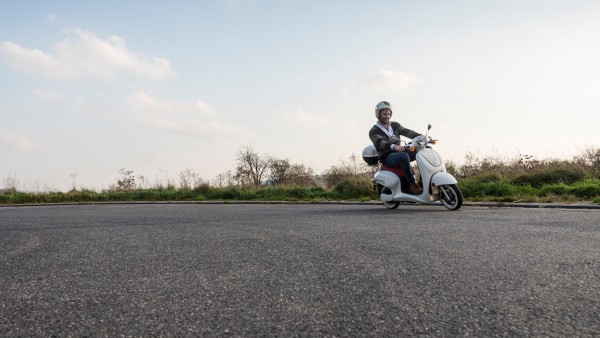 Man driving a scooter on a asphalt road