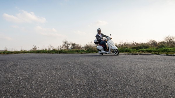 Auf einer asphaltierten Straße fährt ein Mann auf einem Roller