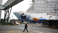 Ein Mitarbeiter geht durch den Hafen, hinter ihm thront das neue Kreuzfahrtschiff