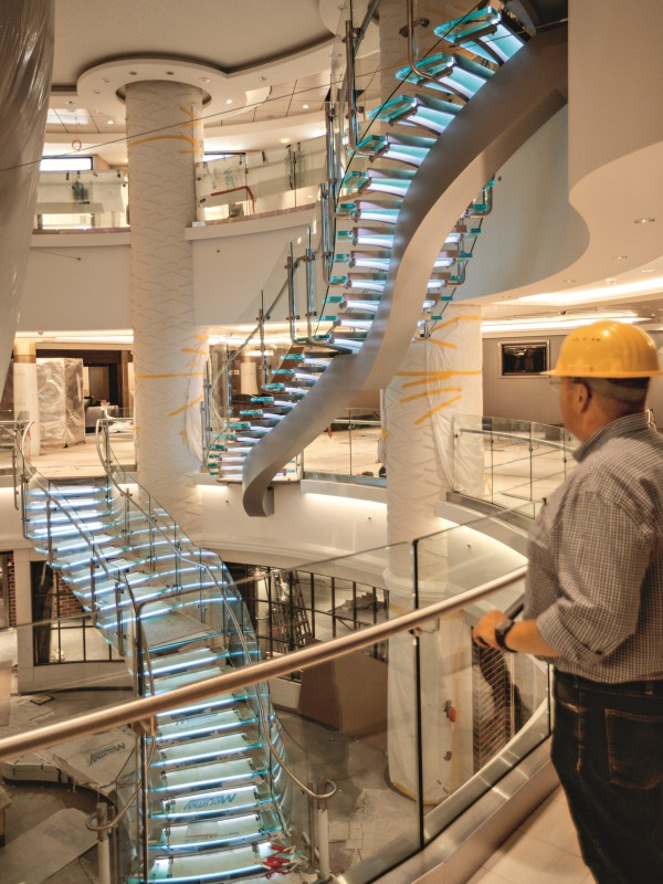 Ein Bauarbeiter blickt hinunter in das Atrium des Schiffes, beleuchtete Treppen führen hinab