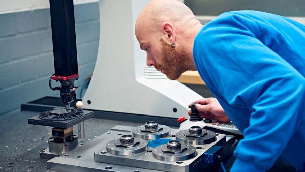 Ein Mann justiert konzentriert eine Plastikfertigungs-Maschine