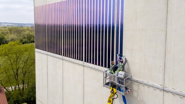 Zei Männer kleben Solarfolien auf ein Hauswand