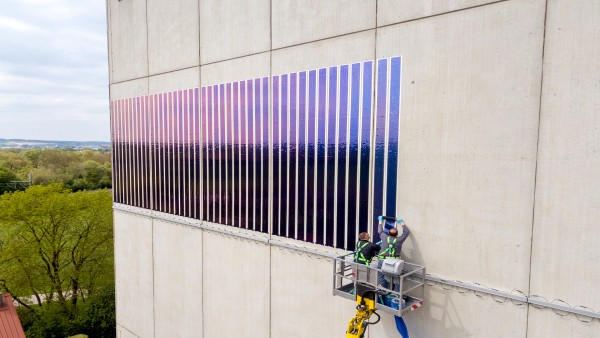 Zei Männer kleben Solarfolien auf ein Hauswand